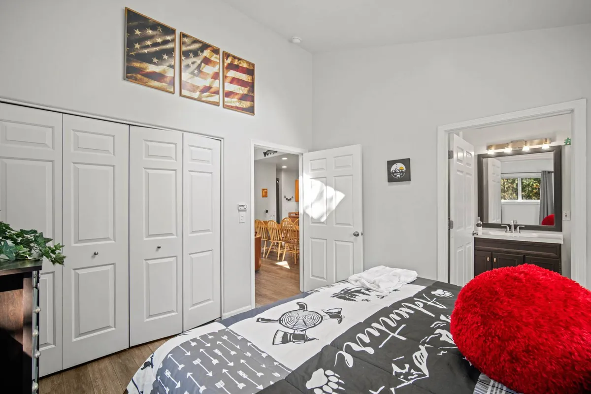 A charming bedroom that features a bed with patterned bedding, a red accent pillow, and decorative wall art. The overall look is warm and inviting, ideal for couples seeking relaxation and rejuvenation. The setting encourages cozy mornings in bed or intimate conversations.